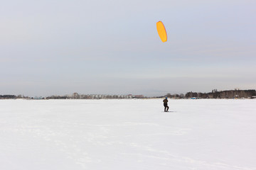 Kiteboarder with orange kite on the snow, Ob reservoir, Novosibirsk, Russia
