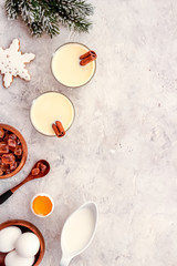 Ingredients for New Year drink eggnog - milk, eggs, cinnamon on grey background top view frame copy space