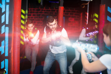 Obraz na płótnie Canvas Excited guy laser tag player in bright beams