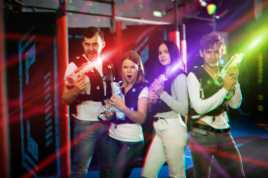 Young people in colorful beams on lasertag arena