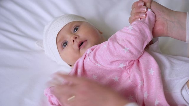 Caring mommy hands wearing warm clothes on cute baby girl, sweet maternity