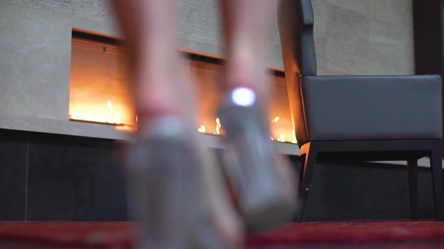 Close up shot of beautiful female feet walking into focus towards a fireplace. Elegantly walking woman.