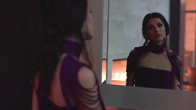 An attractive female model slow motion video from behind showing her reflection in a mirror. 4x slow motion