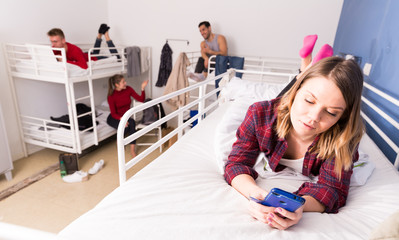 Woman with phone on bed in hostel
