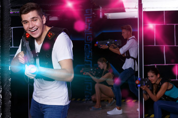 Happy guy holding laser pistol and playing laser tag with his fr
