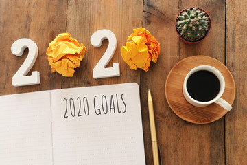 Business concept of top view 2020 goals list with notebook, cup of coffee over wooden desk