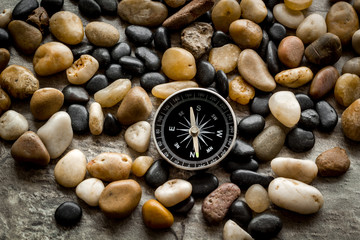 Sea journey, travelling and vacation concept. Compass on rocks and grey background
