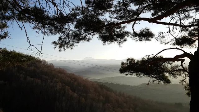 View of mount Elbrus from Kislovodsk Park in Russia. Fields and forests in the haze. Panoramic view. Pine trees in the foreground