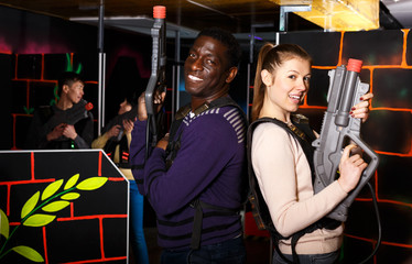Fototapeta na wymiar couple standing back to back holding laser guns during lasertag game