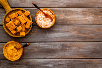 Trendy dessert - salted caramel - melted and cubes on dark wooden background top view frame copy space