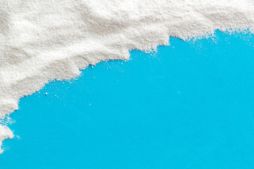 Washing powder scattered on blue background top view frame copy space