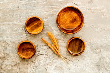 Wooden bowls and ears of wheat on grey background top view