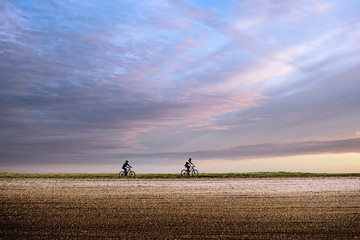 two cyclists riding under a beautiful sunset