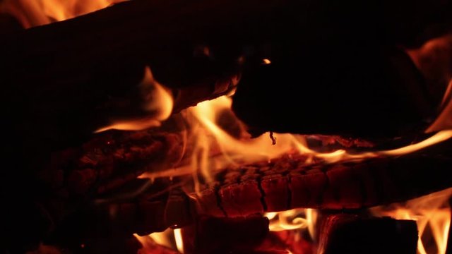 A close up slow mo view of oak fireplace at night. The burned oak glowing by fire heat.