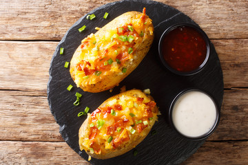 Tasty hot stuffed potatoes with cheddar cheese, green onions and bacon close-up. Horizontal top view