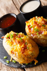 Baked potatoes stuffed with cheddar cheese and bacon closeup. vertical