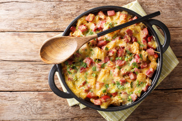 Tasty hot homemade strata with ham, onions, cheese and eggs close-up on the table. Horizontal top view - obrazy, fototapety, plakaty