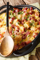 American strata breakfast with ham, onions, cheese and eggs baked in the oven close-up. vertical
