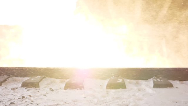 Train move away, bright sun light, snow flakes in air blown behind vehicle, slow motion shot. Beautiful quick scene of last cargo carriage bogie running past, glowing sunshine and cloud of flakes