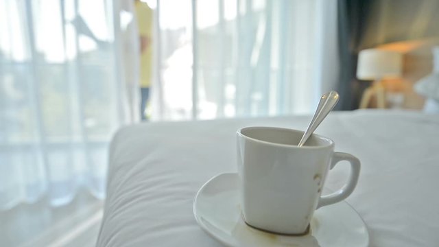 Busy day.Stack papers and coffee cups placed on the bed in the businessman's bedroom. The hand holding the document and bills quickly makes it known that it is a very busy day for this businessman.
