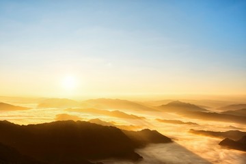 Beautiful scenic sunrise view above the mountains with cloud moving or mist.Colorful orange sky with sunlight in high peak of heaven hill.Nature background concept.