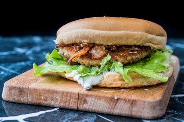 Homemade Salmon Burger with Tartar Sauce, Onion and Lettuce on Marble Board.
