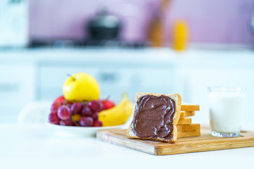 Bread with chocolate cream, fruits and a glass of fresh milk for a sweet healthy breakfast