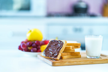 Sandwiches with nut chocolate butter, fruits and a glass of fresh milk for a sweet healthy breakfast