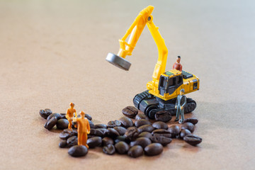 Group of teamwork miniature people, small model human figure and orange tractor and yellow excavator to check coffee beans for made the best coffee on wooden background. Agriculture concept.