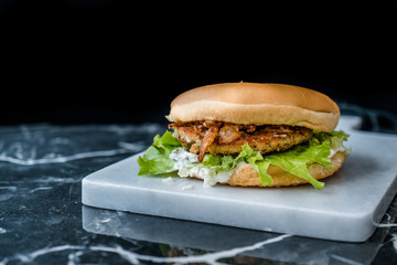 Homemade Salmon Burger with Tartar Sauce, Onion and Lettuce on Marble Board.