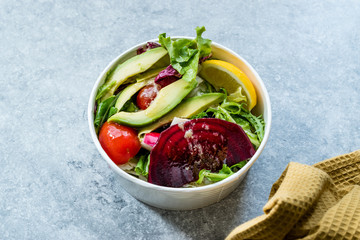 Healthy Fast Food Take Away Salad with Avocado, Beet Slice, Lettuce, Cherry Tomatoes and Sauce in Plastic Box / Package or Container.