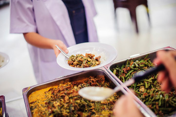 The hands of the needy holding a container to receive free charity food from volunteers : the concept of food assistance