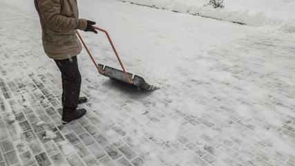 Man cleans the road from snow with a snow shovel