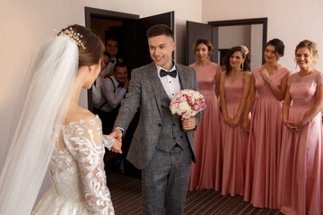 First meeting of bride and groom at wedding day, happy groomsmen and bridesmaids on background