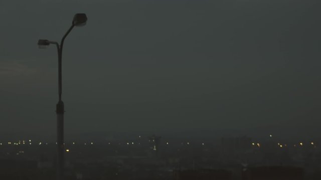 City lights shrouded in fog as street light turns on at dark