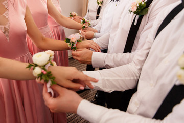 Obraz na płótnie Canvas Wedding tradition. Groomsmen put small bouquets on hands of bridesmaids