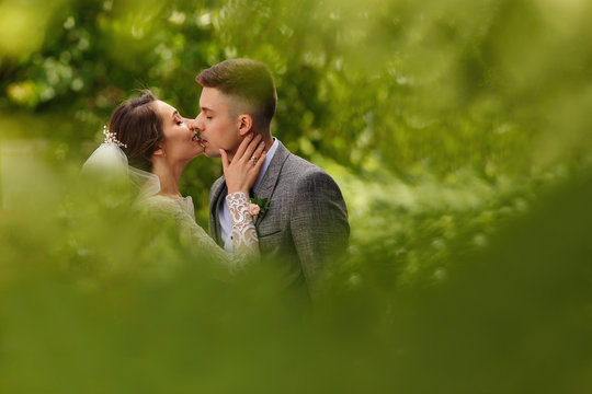 Wedding kiss. Bride and groom kisses on green background
