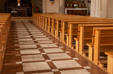 Window light is shining on rows of empty church pews in a Church Sanctuary without any people in it