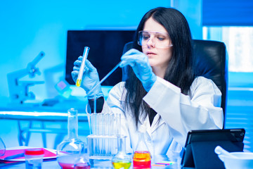 Girl conducts chemical experiments. Concept - Laboratory Assistant. Work with Reagents. A young...