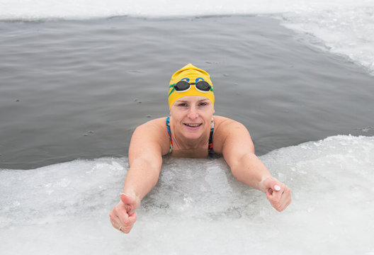 woman in the ice hole in winter in a swimsuit, winter extreme swimming hardening