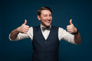 Positive young man in formal suit shows thumbs up