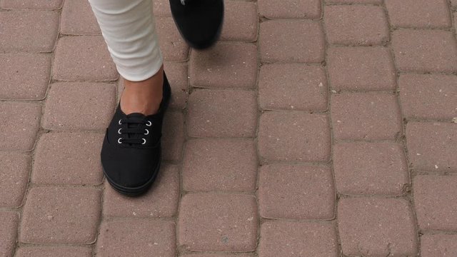 Crumpled soccer ball lie on pavement tiles, woman move back one feet and kick deflate ball out, top view. Loosed game concept