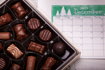 chocolate pralines and calendars photographed as a New Year's and Christmas arrangements on a wooden background