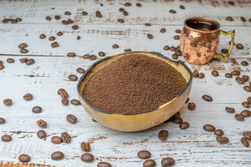 Natural bowl with ground coffee on white wooden table with organic coffee beans and espresso cup