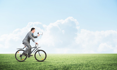 Fototapeta premium Businessman with megaphone in hand on bike