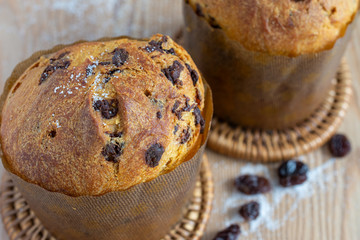 Close-up of two panettones on wooden table with sugar grains and raisins defocused horizontally