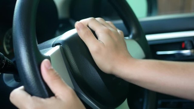 Close up inside vehicle of female hand pushing on steering wheel and honking with angry. Technology and transportation concepts.