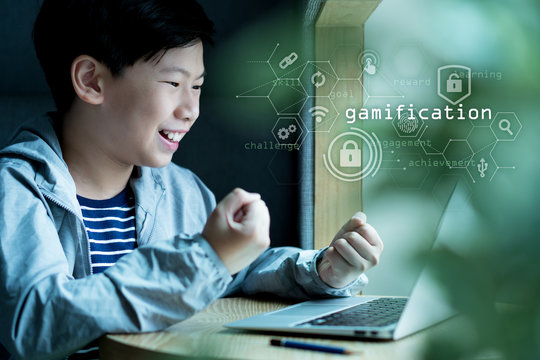 Young Smart Looking Asian Preteen Boy Is Happy And Excited As He Complete And Achieve Next Level In His Online Gamification Lessons On Computer Laptop. Gamification, Self Learning And Future Education