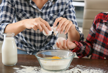 Happy mother and daughter cooking pastry at home, closeup