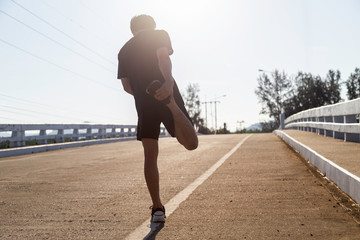 Asian male runner is stretching on the street before doing work out in the morning